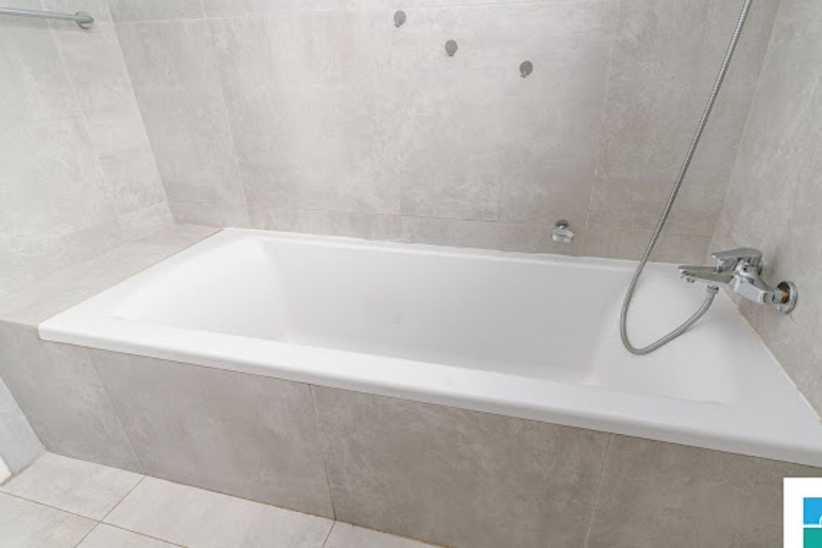 Modern bathroom featuring a built-in bathtub with contemporary grey stone-look tiling and chrome fixtures.