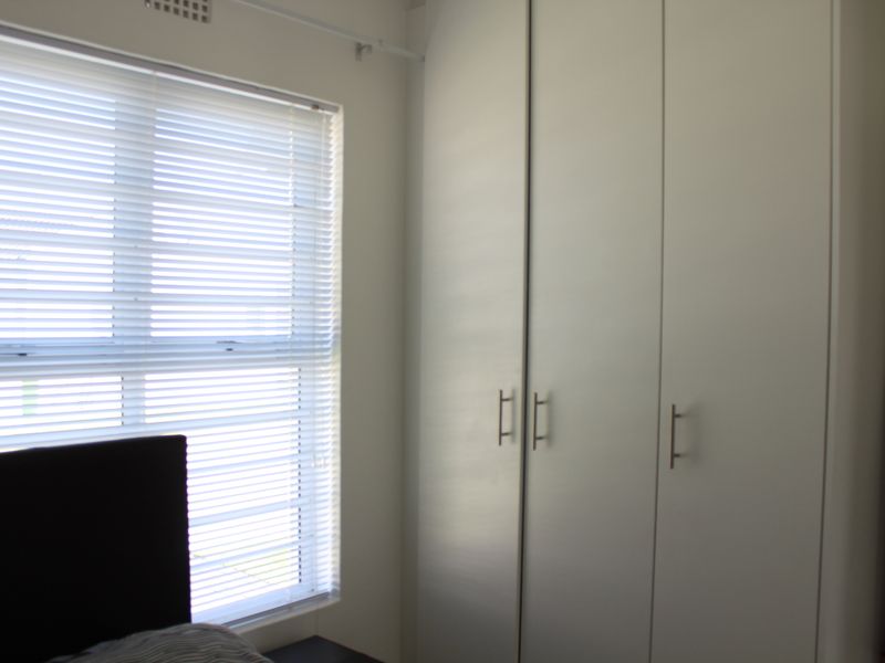 A bedroom featuring a built-in wardrobe and venetian blinds over the window.