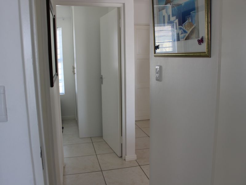 A clean and functional hallway featuring neutral tiled flooring and white internal doors, providing access to various rooms within the townhouse.