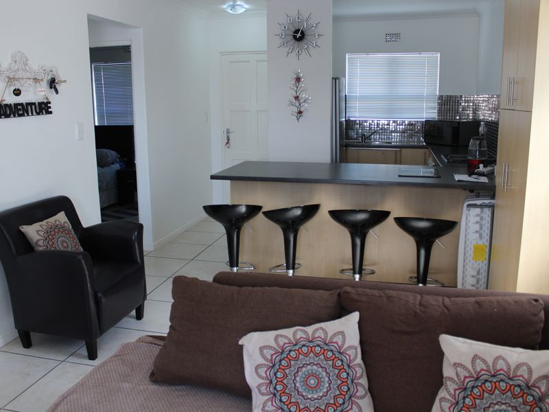 Open plan living area featuring a breakfast bar, kitchen cabinetry, and tiled flooring, creating a functional and connected space for daily living.