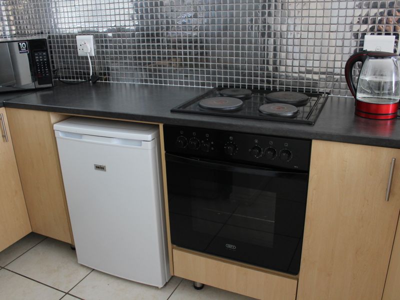 Compact kitchen area featuring a built-in oven, electric hob, laminate cabinetry, and a modern mosaic tile backsplash.