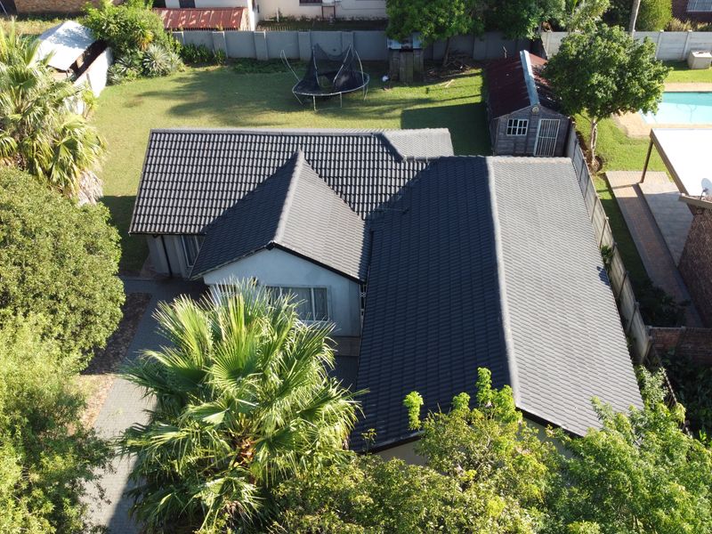 Aerial view of the property featuring a tiled roof, spacious garden, swimming pool, and a paved patio area.