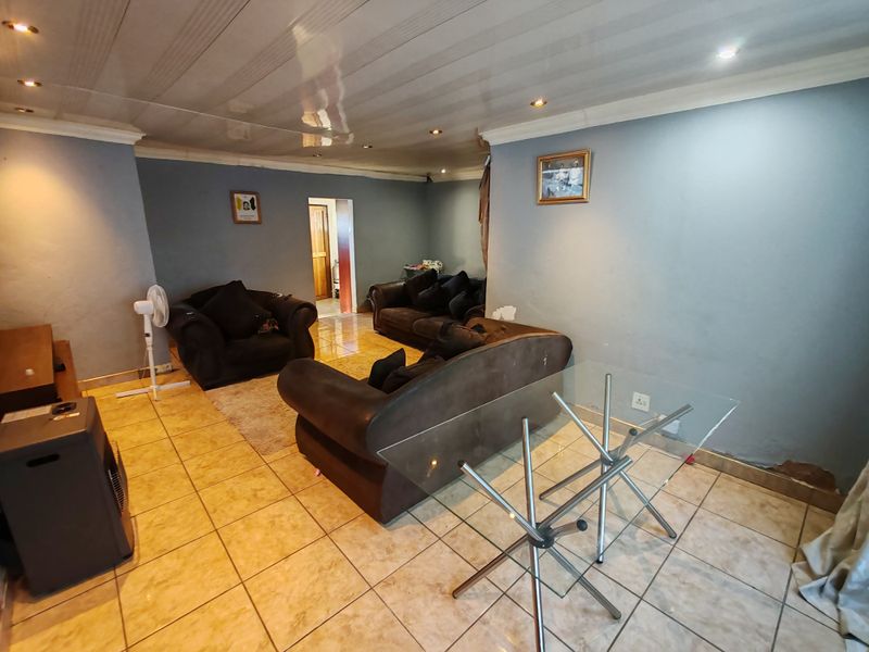A living room featuring tiled flooring and recessed ceiling lighting, requiring minor wall repairs to improve the overall finish.