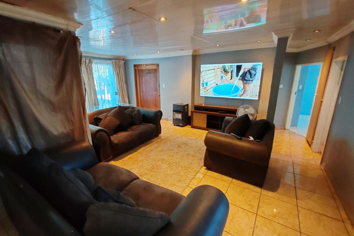 A spacious living room featuring tiled flooring, recessed downlighting, and a glossy ceiling finish, providing a functional and comfortable family living area.