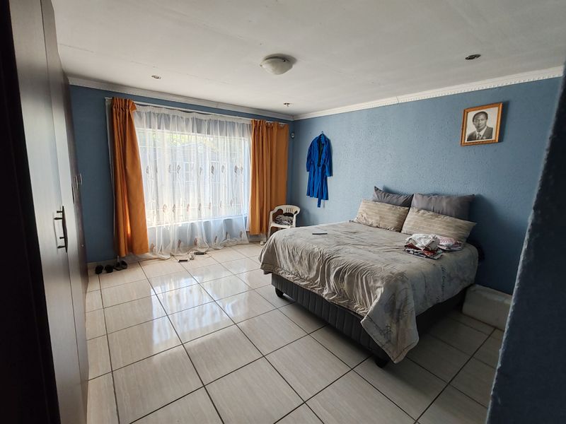 Spacious bedroom featuring tiled flooring, built-in wardrobe storage, and recessed ceiling lighting.