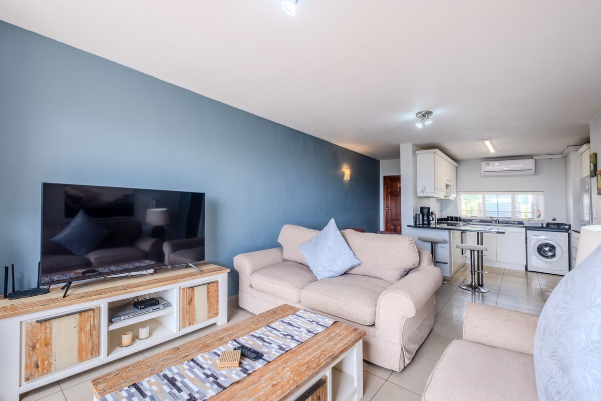 An open-plan living area featuring a modern kitchen with built-in cabinetry, tiled floors, and a split-system air conditioner, creating a functional and cohesive space.