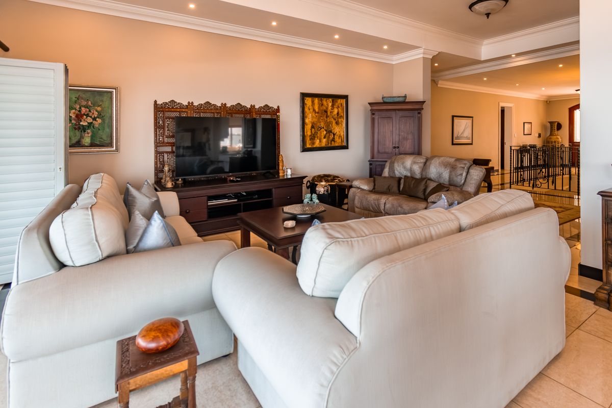 Spacious living room featuring recessed ceiling lighting, crown molding, and neutral tiled flooring, creating a comfortable and well-maintained living space.