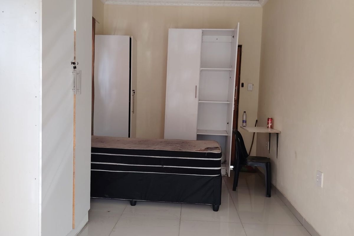 A functional bedroom featuring tiled flooring, coved ceilings, and built-in wardrobe storage.