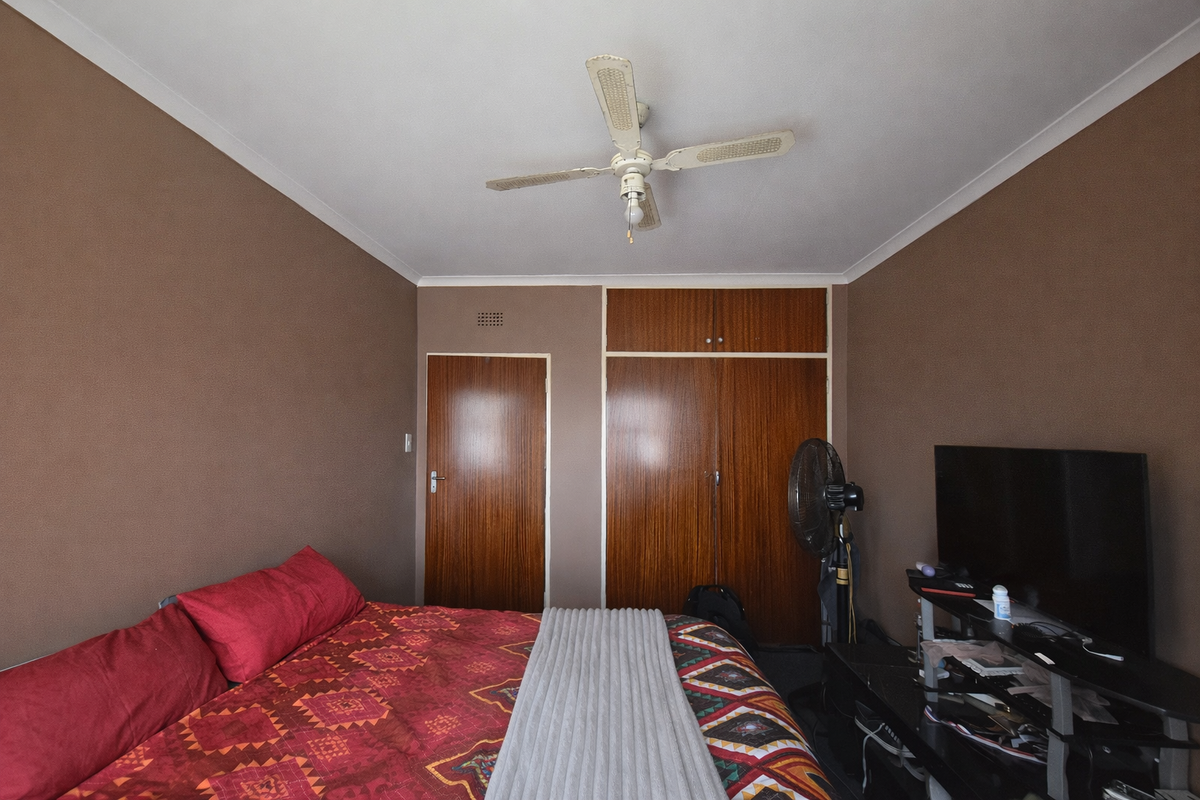 A bedroom featuring built-in wooden cupboards, a ceiling fan, and coving detail.