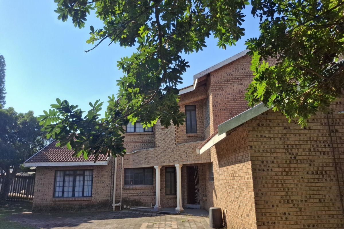A double-story face-brick residential house featuring a paved courtyard area and classic architectural detailing.