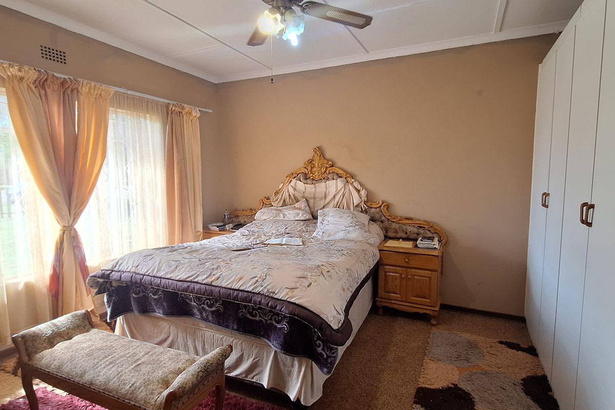 A bedroom featuring built-in wardrobes, a ceiling fan, and large windows allowing natural light.