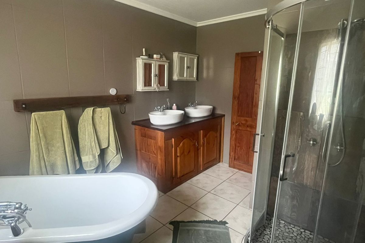 A bathroom featuring a freestanding bathtub, a separate glass-enclosed shower, and a wooden vanity with dual vessel sinks.