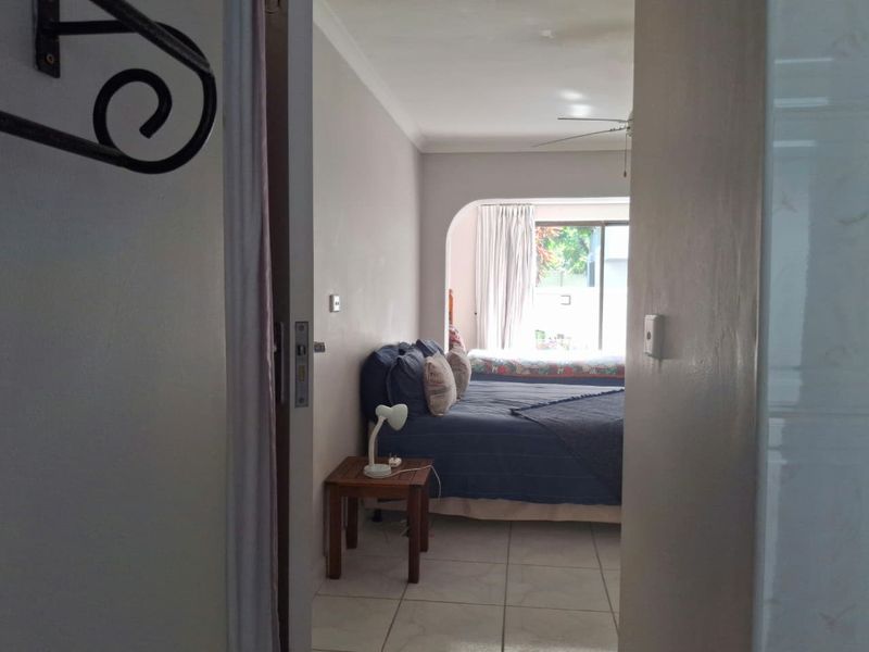A bedroom featuring tiled flooring, a ceiling fan, and a sliding glass door leading to an outdoor area.