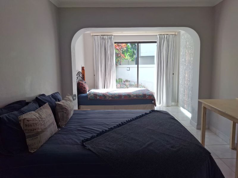 Spacious bedroom featuring an arched transition area, tiled flooring, and a sliding glass door providing access to the exterior.