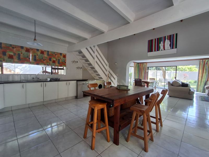 Spacious open-plan kitchen and living area featuring exposed beam ceilings, tiled flooring, and direct access to the rear garden through sliding glass doors.