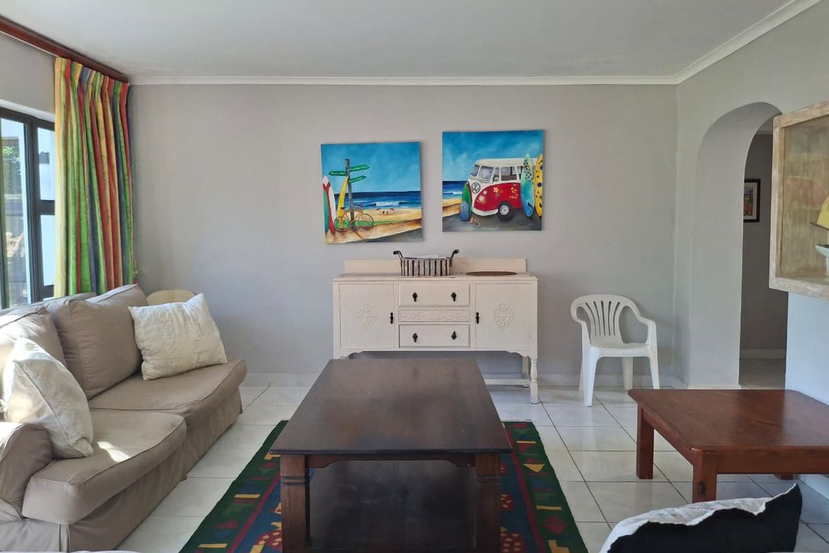 A bright living room featuring neutral tiled flooring, a classic archway entrance, and coved ceiling details, offering a comfortable and functional living space.