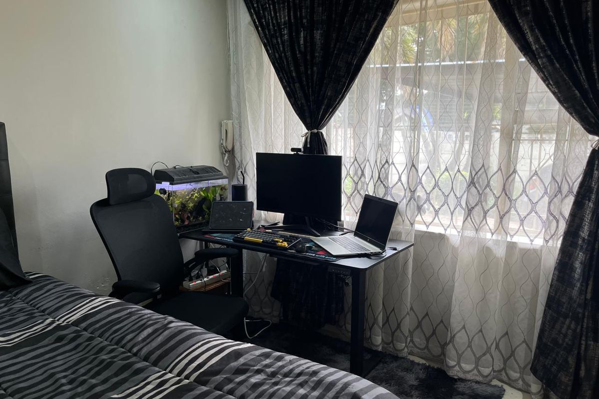 A bedroom featuring a window with installed curtain rails, providing natural light and a view of the exterior.