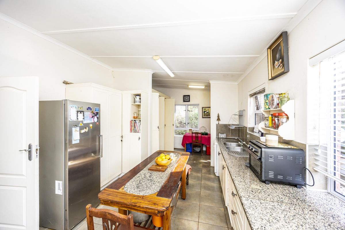 A functional kitchen featuring granite countertops, ample built-in cabinetry, and tiled flooring, with a practical layout and direct access to the dining area.