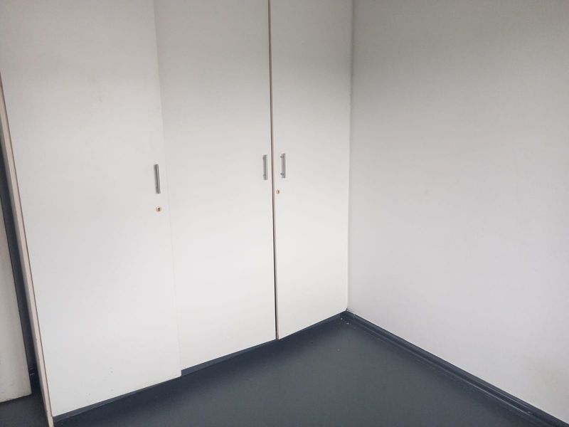 A simple, empty bedroom space featuring white built-in cupboards and dark flooring, offering a clean canvas for personalization.