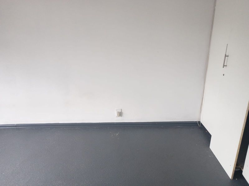 An empty bedroom featuring dark painted flooring, white walls, and a built-in cupboard with modern hardware.