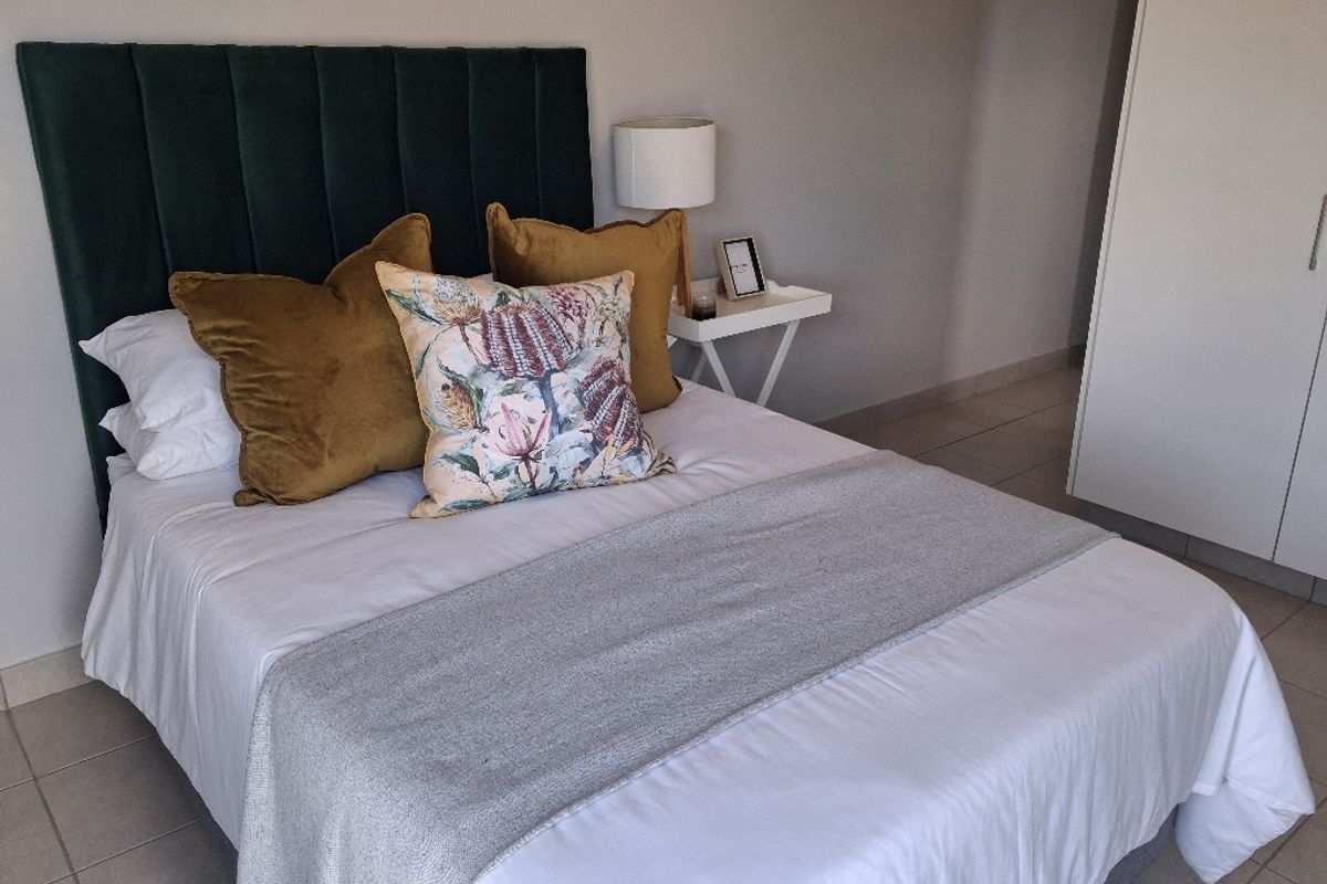 A well-maintained bedroom featuring neutral tiled flooring and a built-in wardrobe, offering a clean and functional living space.