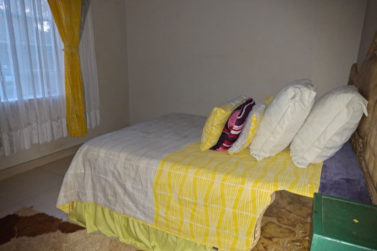 A bedroom featuring tiled flooring and a window with curtains, providing a functional and simple living space.