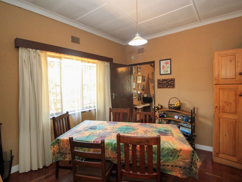 Dining room featuring wooden parquet flooring, a built-in wooden cupboard, and a window with security bars, offering a traditional layout.