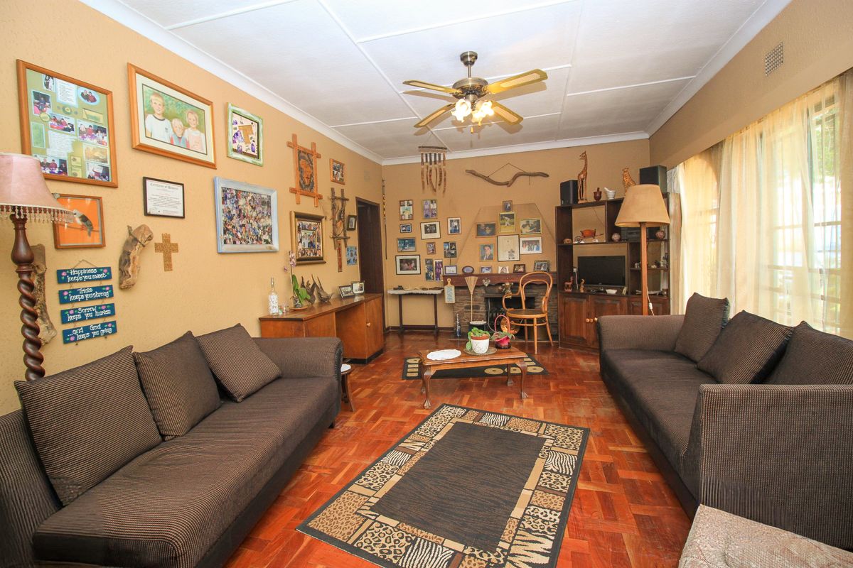 A living room featuring traditional parquet flooring, a central ceiling fan, and a built-in fireplace with integrated shelving.