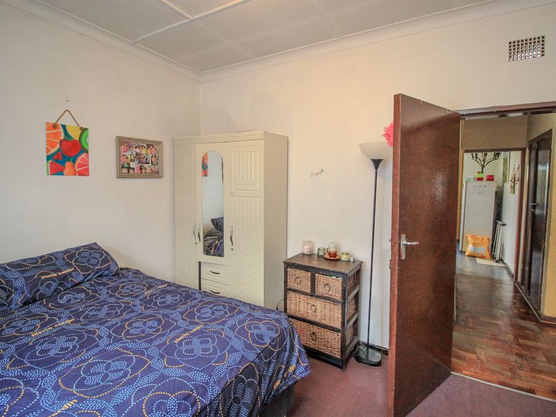 A standard bedroom featuring carpeted flooring and a timber door, providing access to the hallway.
