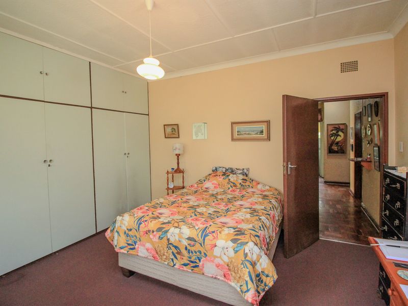 A bedroom featuring built-in cupboards, coved ceilings, and carpeted flooring, offering a functional space with potential for cosmetic updates.