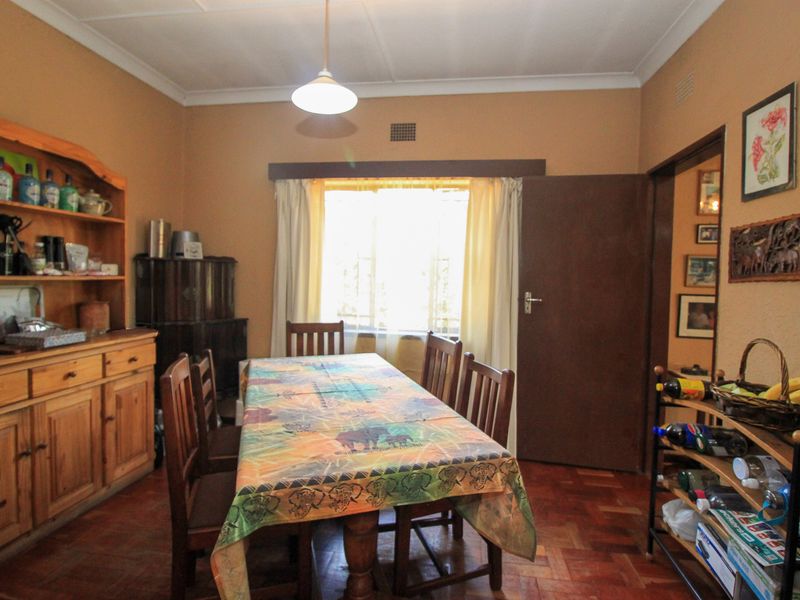 A traditional dining room featuring classic parquet flooring, coved ceilings, and a large window, offering a warm and functional space for family meals.
