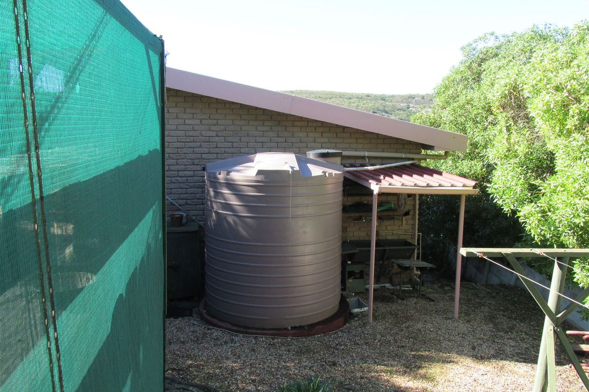 Rear exterior view showing a brick building facade, a large water storage tank, and a covered utility area with gravel ground cover.