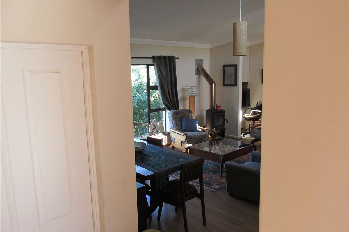 A view into a living area featuring a wood-burning stove, laminate flooring, and access to the outdoors through a sliding glass door.