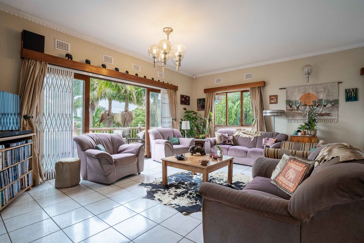 Spacious living room featuring tiled flooring, crown molding, and large sliding glass doors that provide access to the outdoor area.