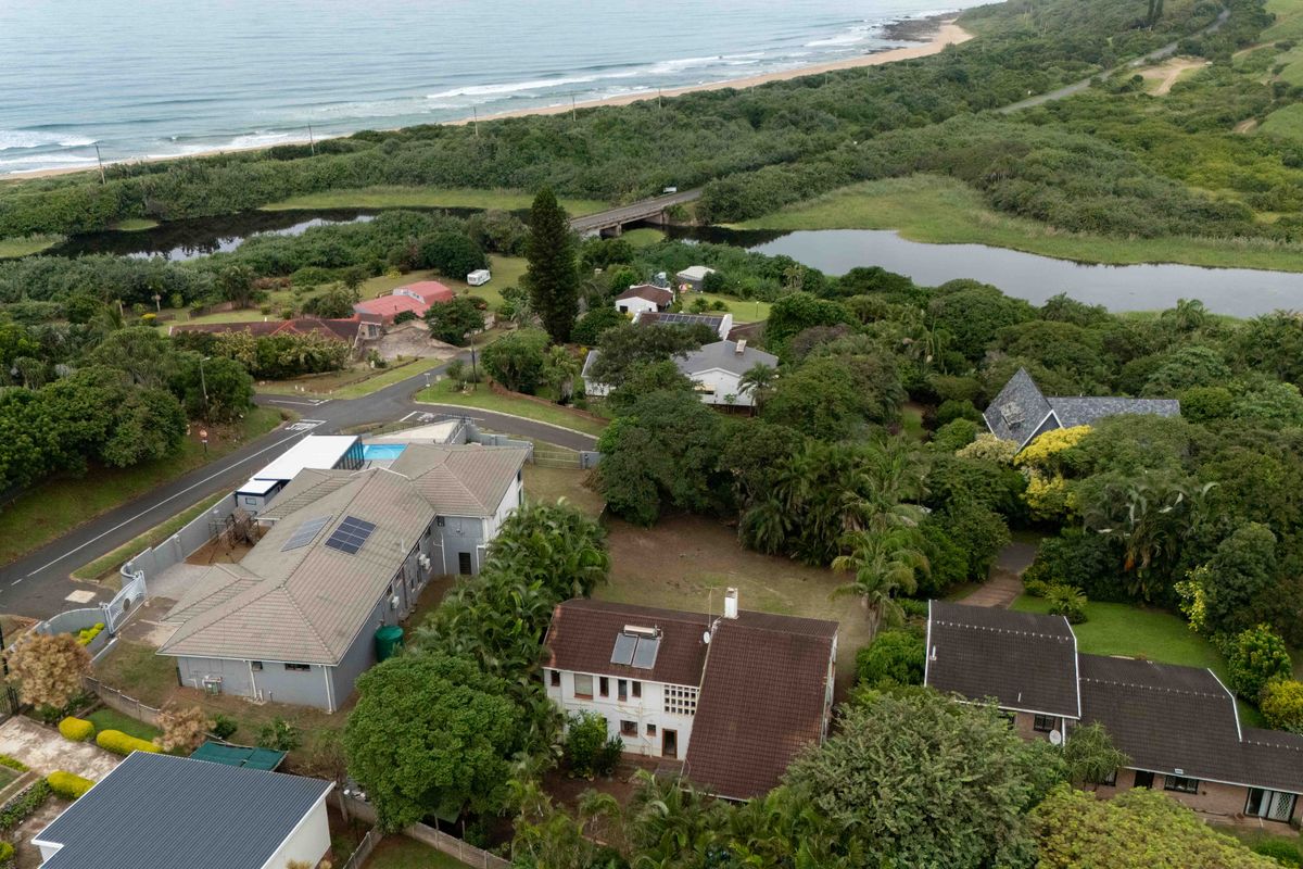 Aerial view of the property and surrounding coastal neighborhood, showcasing the roof structure, solar water heating system, and proximity to the beach.