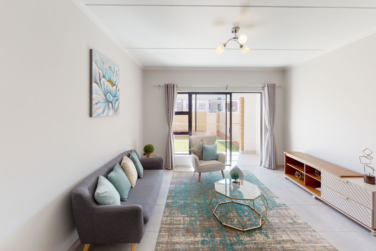 A bright and modern living room featuring tiled flooring and large sliding glass doors that open onto an outdoor patio area.