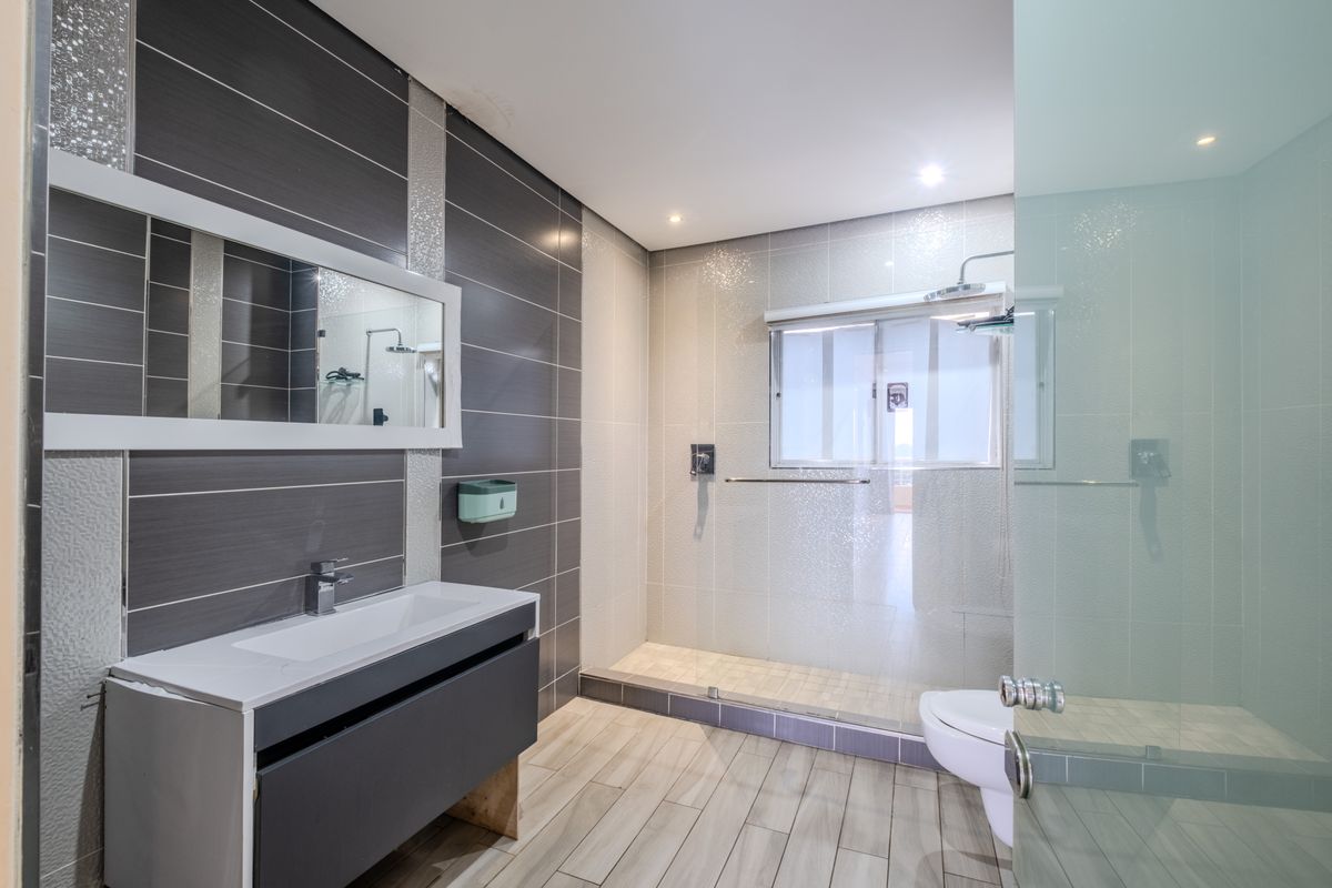 Modern bathroom featuring a walk-in shower with glass enclosure, vanity unit with basin, and contemporary wall tiling.