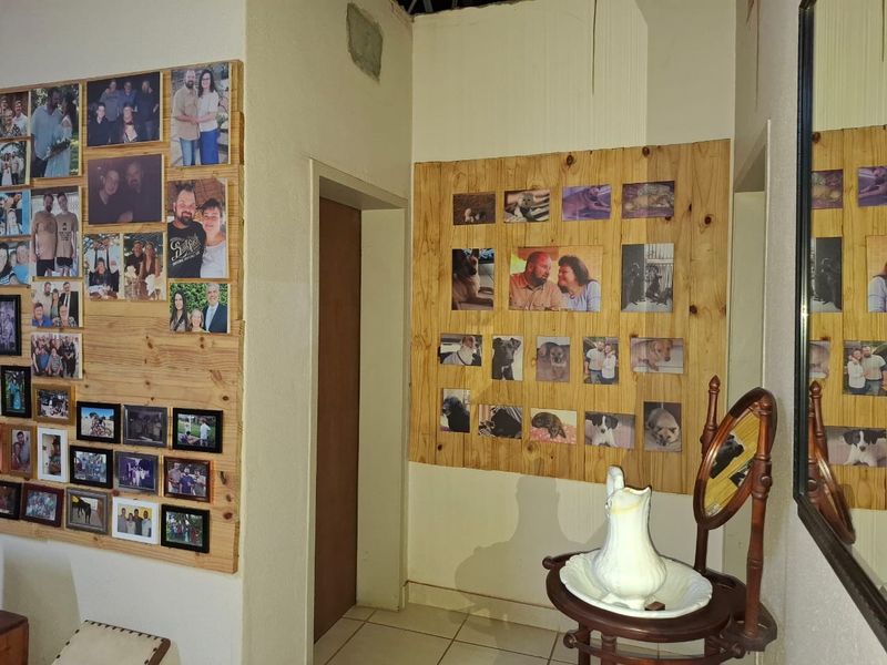 A hallway area featuring tiled flooring and decorative timber wall paneling, currently used for displaying personal photographs.