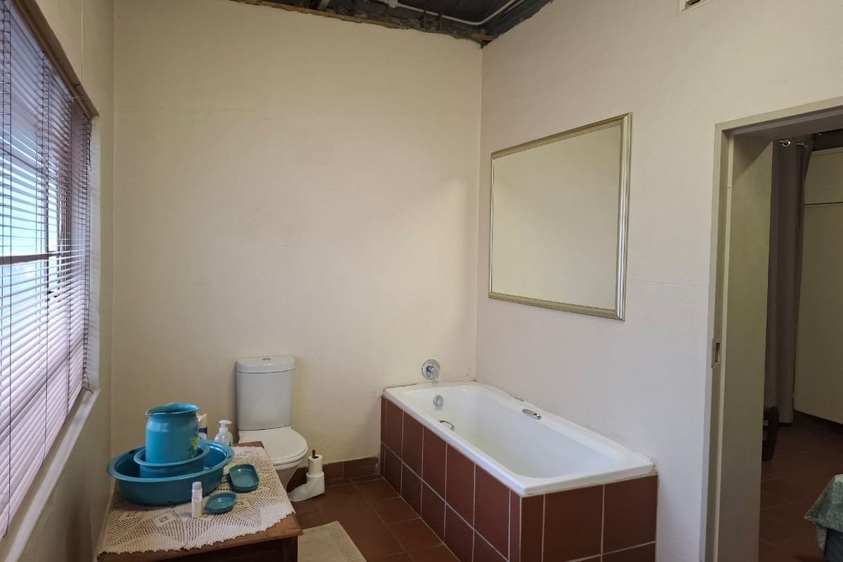 A bathroom featuring a bathtub and toilet, currently requiring ceiling repairs and cosmetic updates to the wall finishes and tiling.