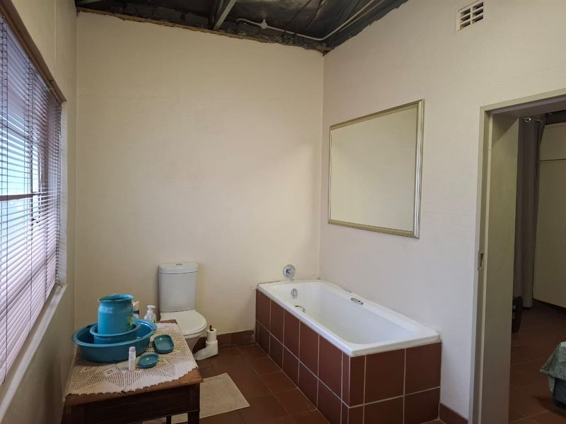 A bathroom featuring a bathtub and toilet, currently requiring ceiling repairs and cosmetic updates to the wall finishes and tiling.