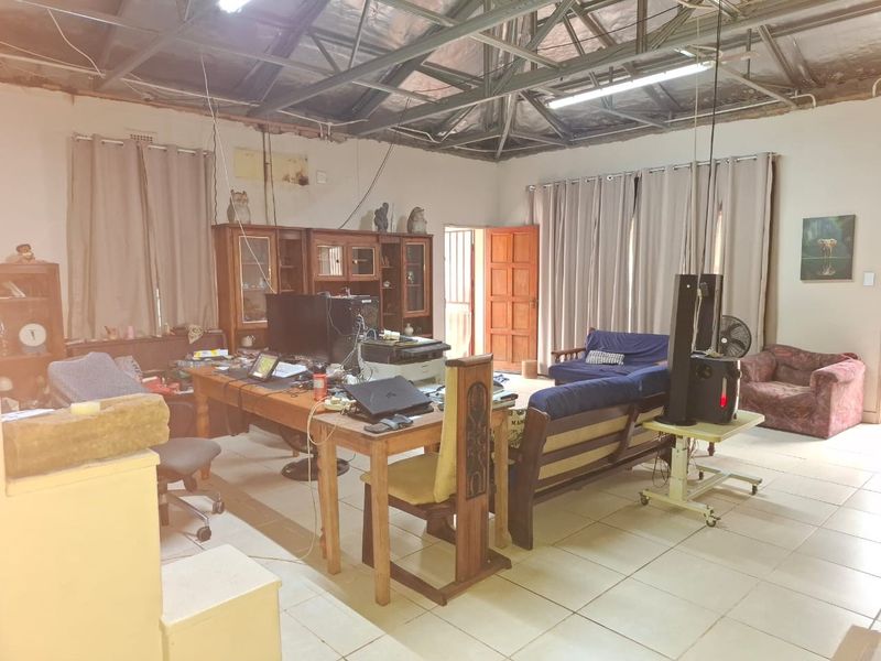 Spacious living area featuring exposed steel roof trusses, ceramic tiled flooring, and direct access to an exterior door.