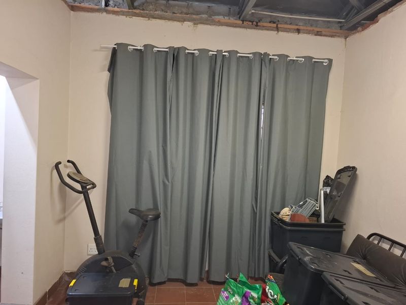A bedroom space currently undergoing renovation with unfinished ceiling framework and tiled flooring.
