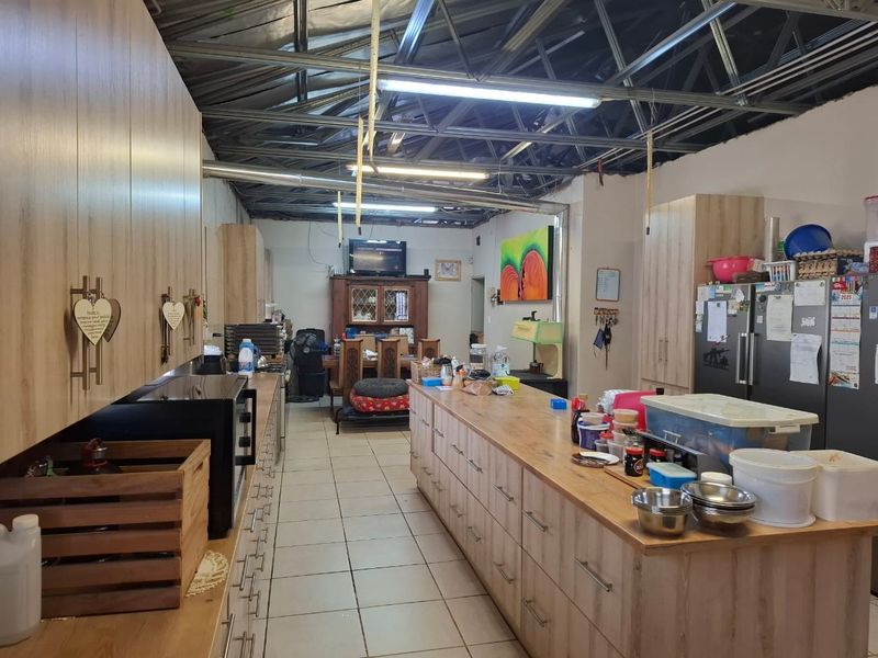 Open-plan kitchen and living area featuring extensive built-in cabinetry, a large central island, and an industrial-style exposed steel roof structure.