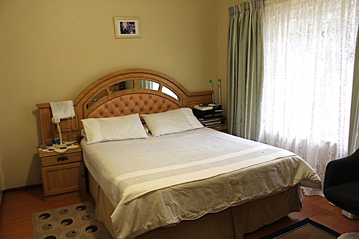 A standard bedroom featuring laminate flooring and window treatments, providing a functional and neutral space for rest.