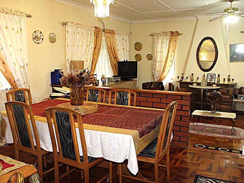Open plan living and dining area featuring traditional parquet flooring, a brick partition wall, and a ceiling fan.