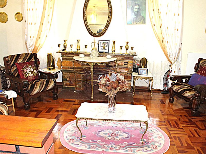 A traditional living room featuring a stone fireplace and classic parquet flooring, offering a warm and established atmosphere.