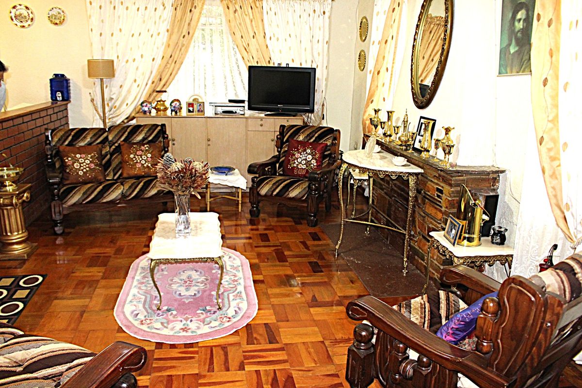 A traditional living room featuring classic parquet flooring and a stone-clad fireplace, offering a warm and established atmosphere.