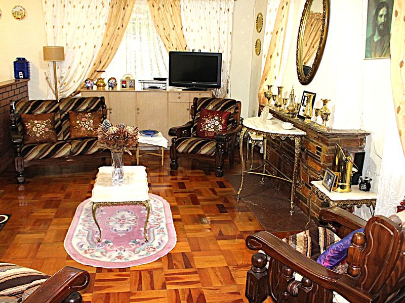 A traditional living room featuring classic parquet flooring and a stone-clad fireplace, offering a warm and established atmosphere.