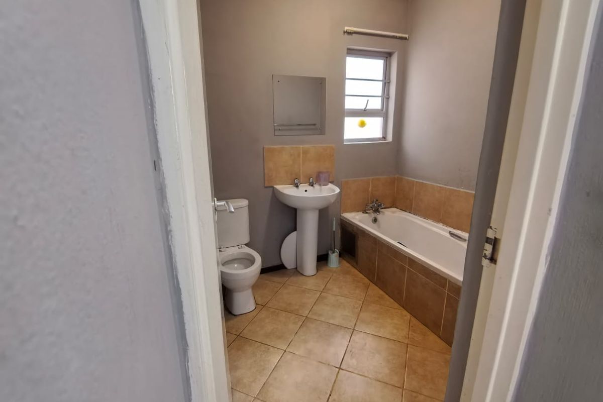 A functional bathroom featuring a pedestal basin, toilet, and bathtub with tiled splashbacks and flooring.