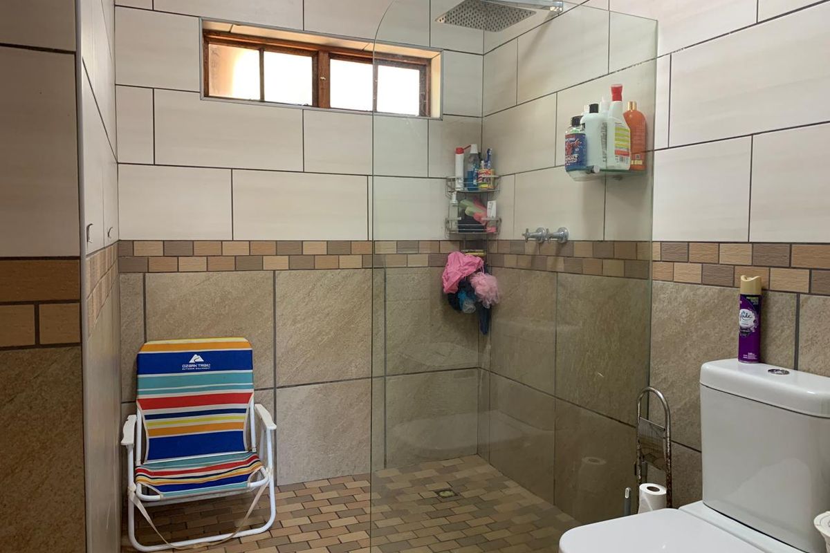A functional bathroom featuring a walk-in shower with a glass screen, rain shower head, and tiled finishes throughout.